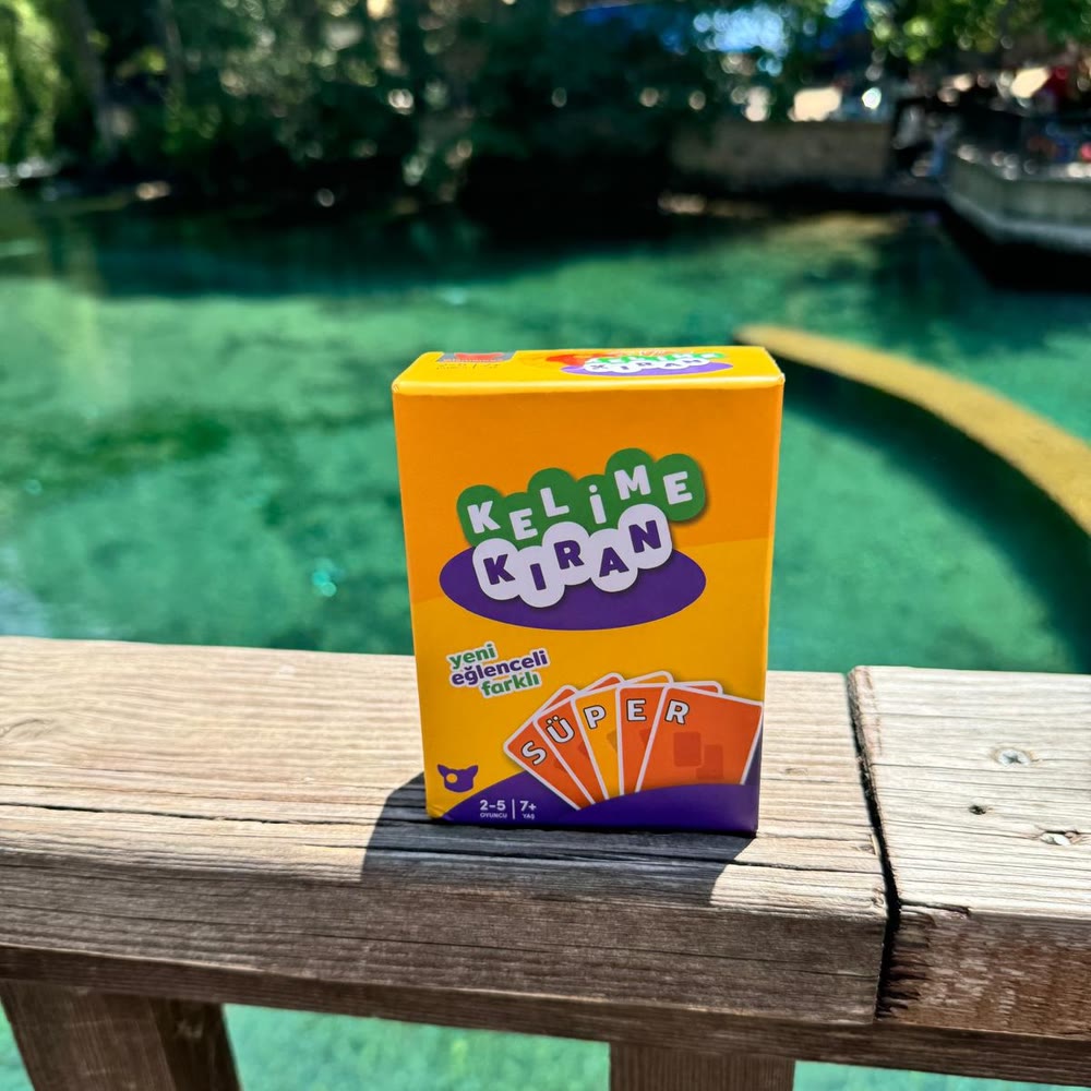 The Kelime Kıran box on a wooden railing above clear green water